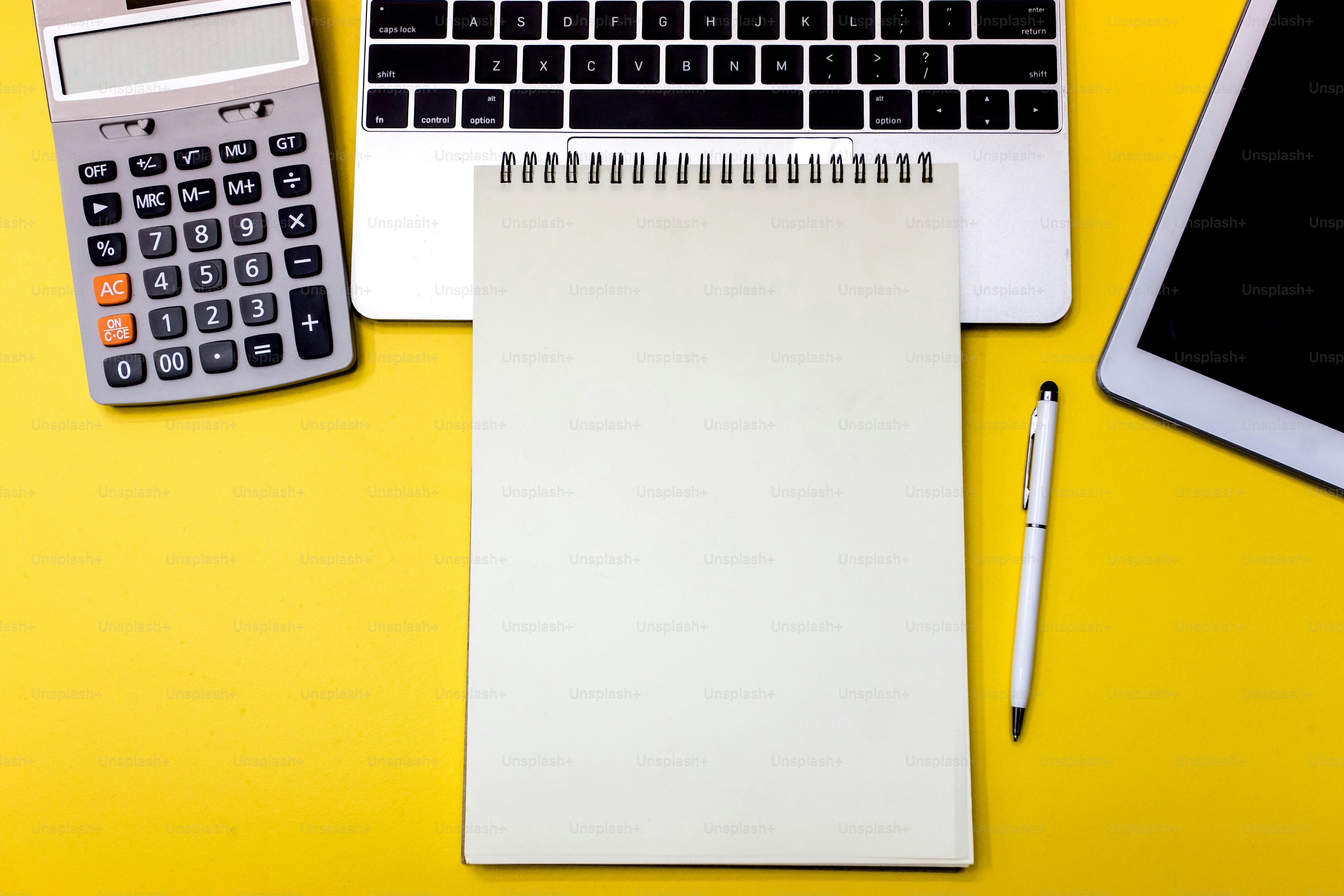 Table de bureau jaune avec ordinateur portable vierge, tablette et calculatrice. Vue de dessus