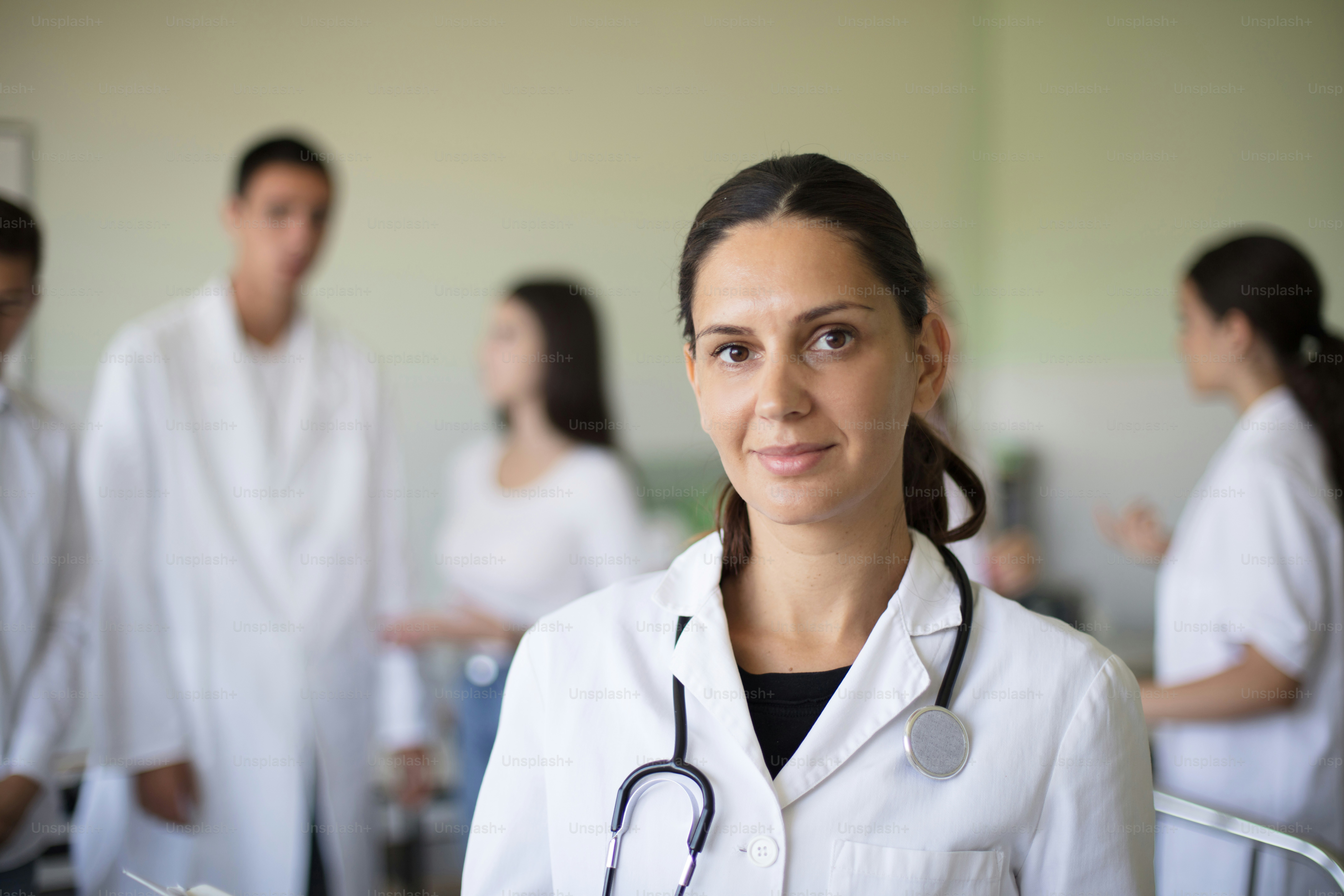 Portrait of female doctor in hospital. Group of people in patient room