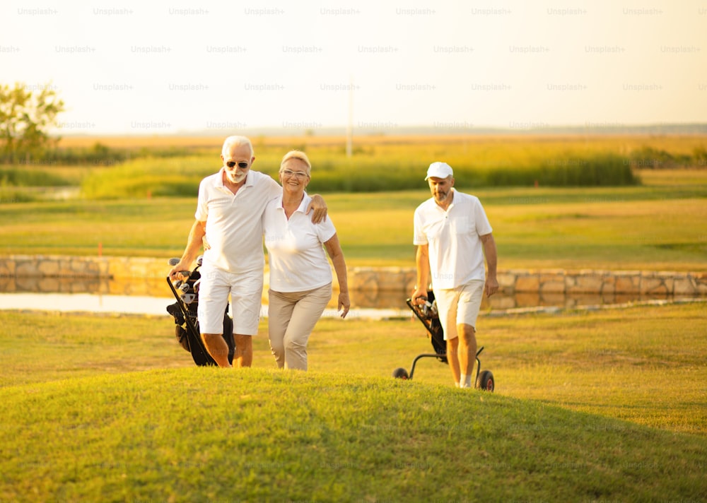 Tres golfistas senior. La atención se centra en el hombre y la mujer.