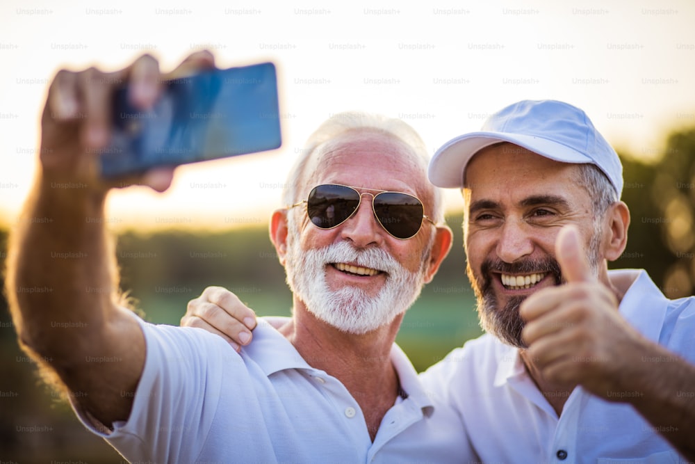 携帯電話で自画像を撮る2人の先輩ゴルファー。