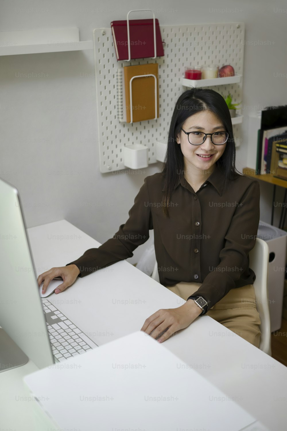 Happy young woman designer sitting at her office desk and smiling to camera.