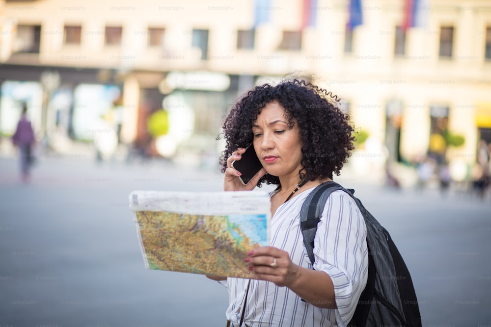 지도를 보고 있는 관광객. 거리에서 지도를 읽고 전화로 이야기하는 관광객.