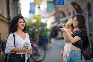 Woman taking photo of her friend. Two tourist women on street.