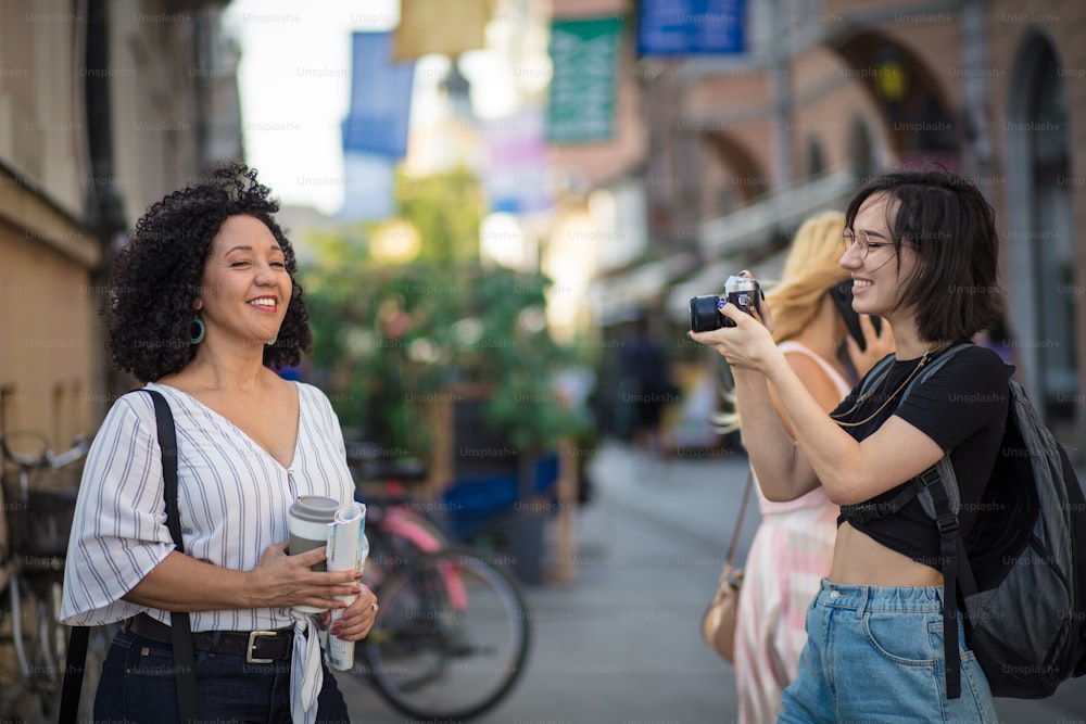 Frau, die ein Foto von ihrer Freundin macht. Zwei Touristinnen auf der Straße.