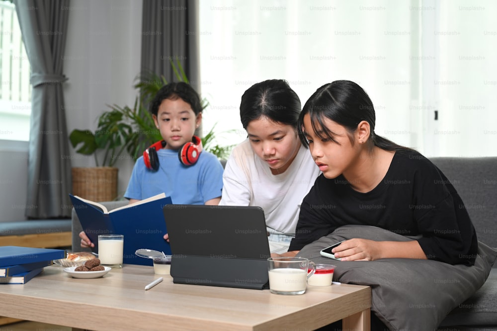 Young asian girl sitting on sofa in living room using computer tablet and enjoy leisure weekend together.