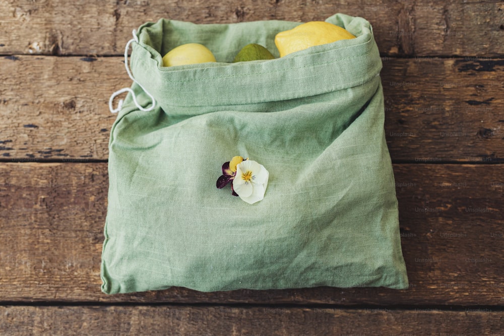 친환경 플라스틱 무료 식료품 배달 및 쇼핑. 신선한 사과, 아보카도, 소박한 나무 테이블에 꽃이 든 면봉에 레몬. 폐기물 제로. 재사용 가능한 가방에 담긴 유기농 과일 및 채소