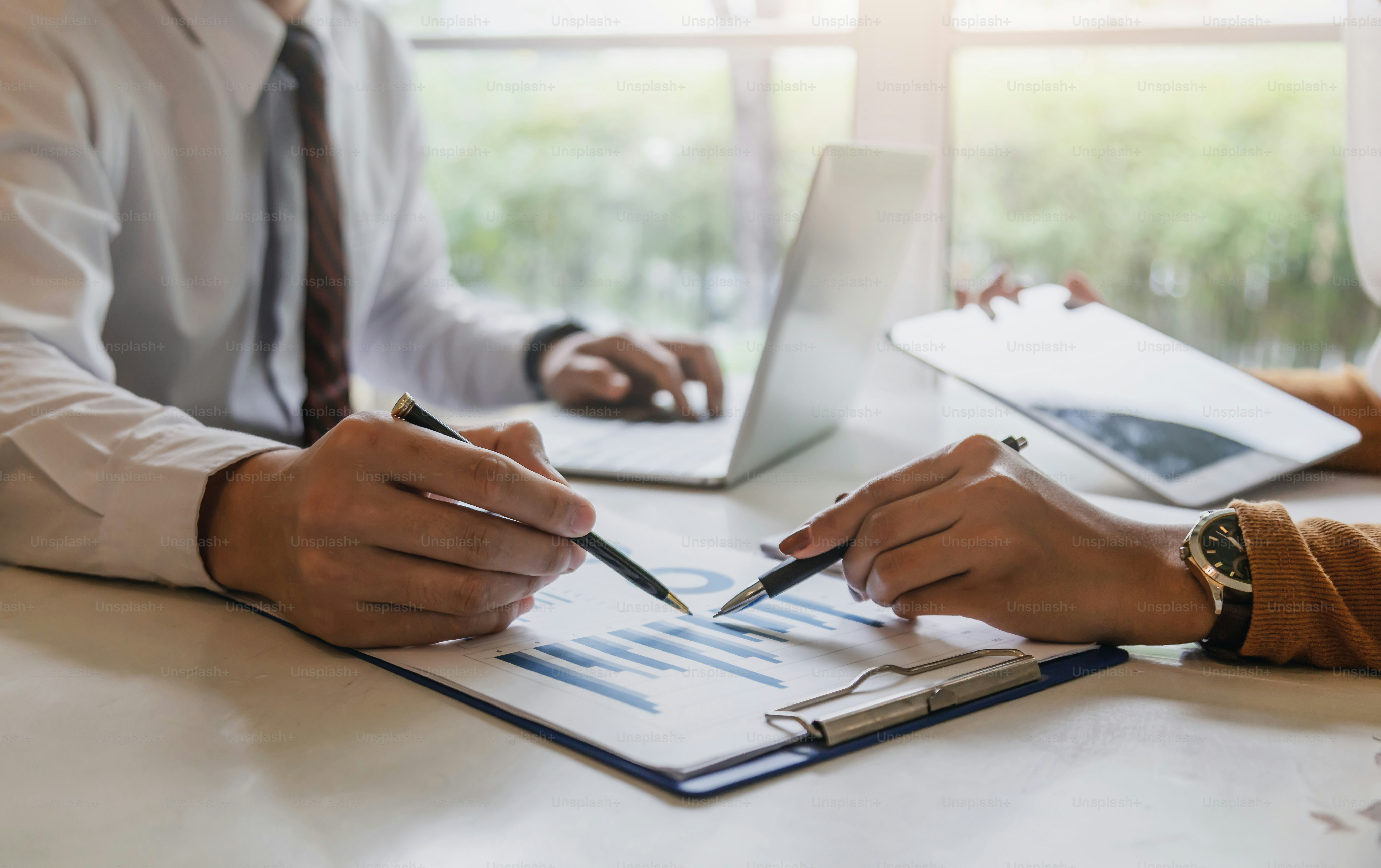 Business partner pointing to the data graph to illustrate the growth of the investment.
