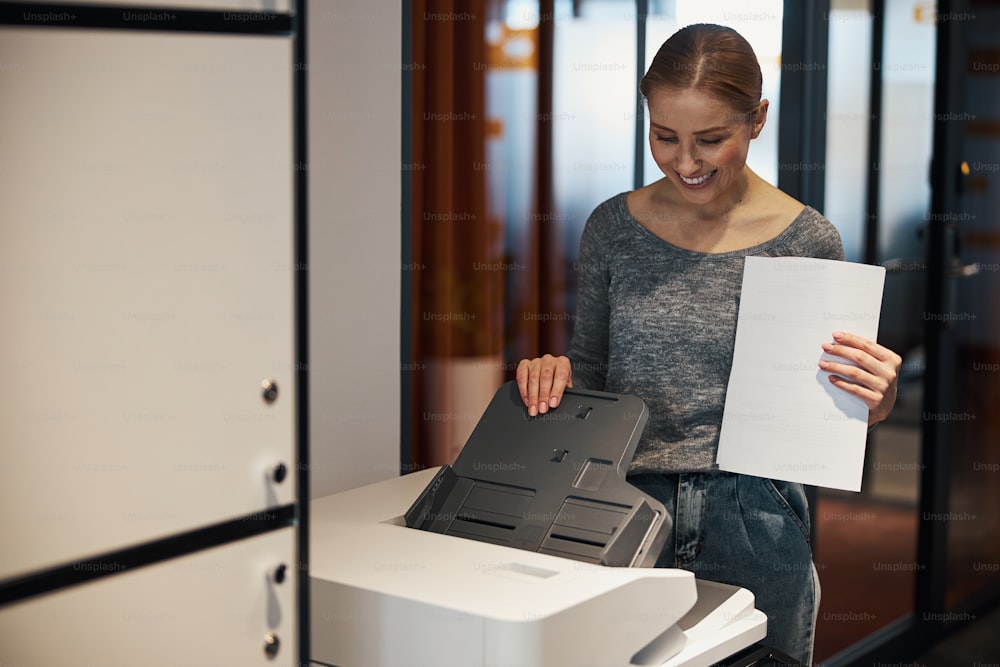 Smiling office worker getting the printing device ready for work