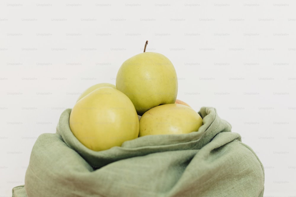 Umweltfreundliche plastikfreie Lebensmittellieferung und -einkauf. Frische Äpfel in Öko-Baumwolltasche auf weißem Hintergrund. Null Abfall. Bio-Früchte in wiederverwendbarem grünen Beutel.  Nachhaltiger Lebensstil