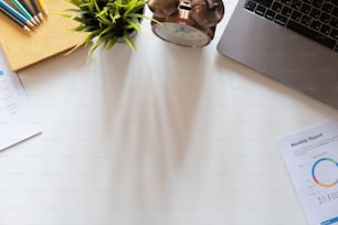 Draufsicht Hand des Buchhalters mit Taschenrechner am Arbeitsplatz mit Kopierplatz, Taschenrechner und Pflanze auf weißem Schreibtischhintergrund, Buchhaltung Arbeitsplatzkonzept.