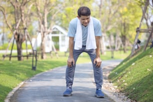 portrait of sporty healthy mature male in hoodie and running shoes exercising outdoors, practicing side lunges. Elderly bearded man in sportswear warming up before morning run in park