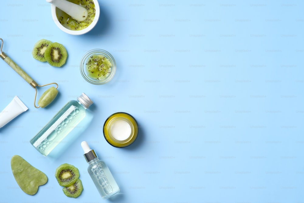 Natürliche Bio-SPA-Kosmetikprodukte mit geschnittenen Kiwis. Draufsicht pflanzliche Hautpflege-Schönheitsprodukte auf blauem Hintergrund. Banner Mockup für Schönheitssalon
