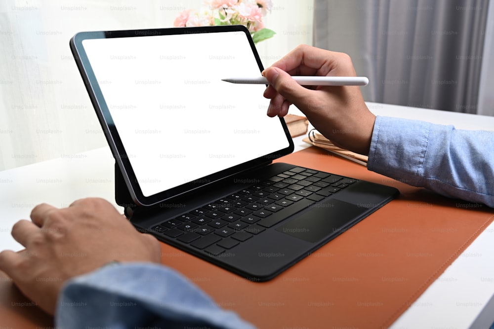 Close up view man holding stylus pen writing on empty screen of computer tablet.