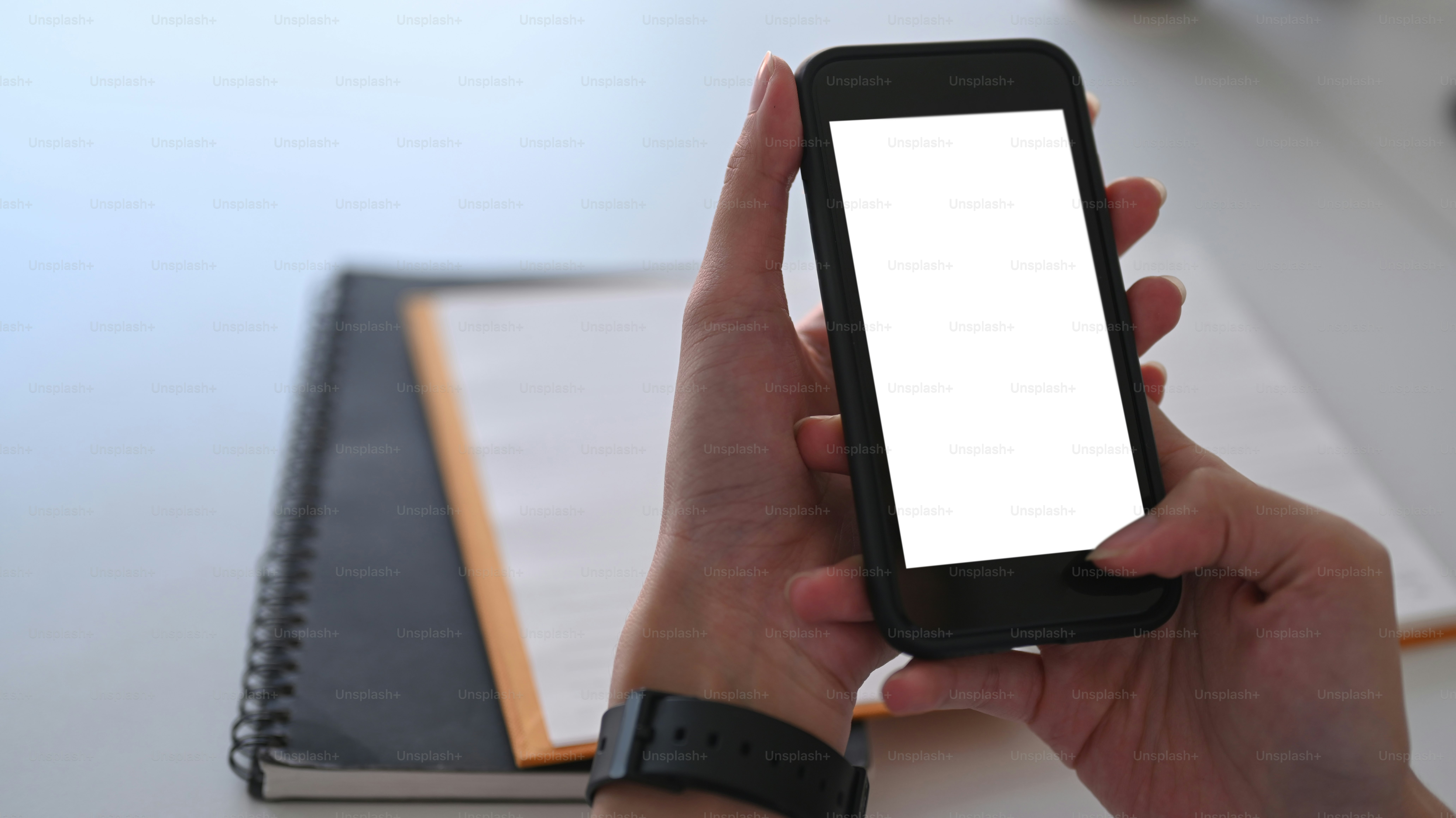 Gros plan sur les mains d’une femme tenant un téléphone intelligent avec écran blanc.