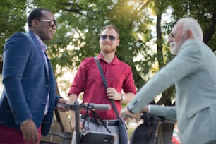 Colleagues met on the way to work. Three business colleagues standing outdoors and discussing.