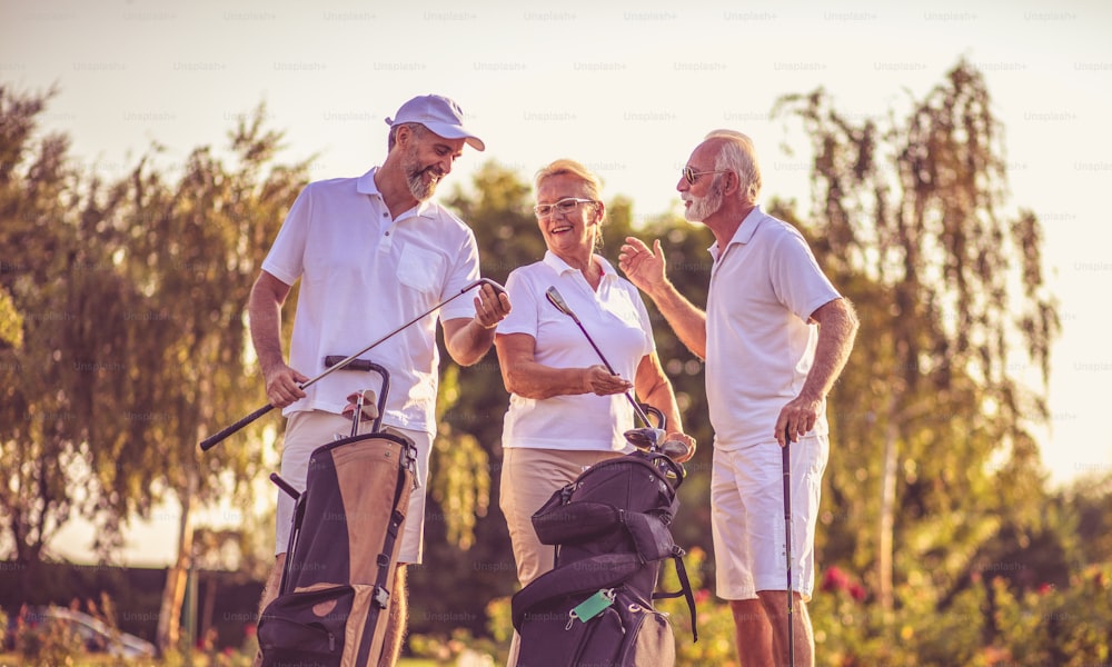 Senior friends on golf court talking.