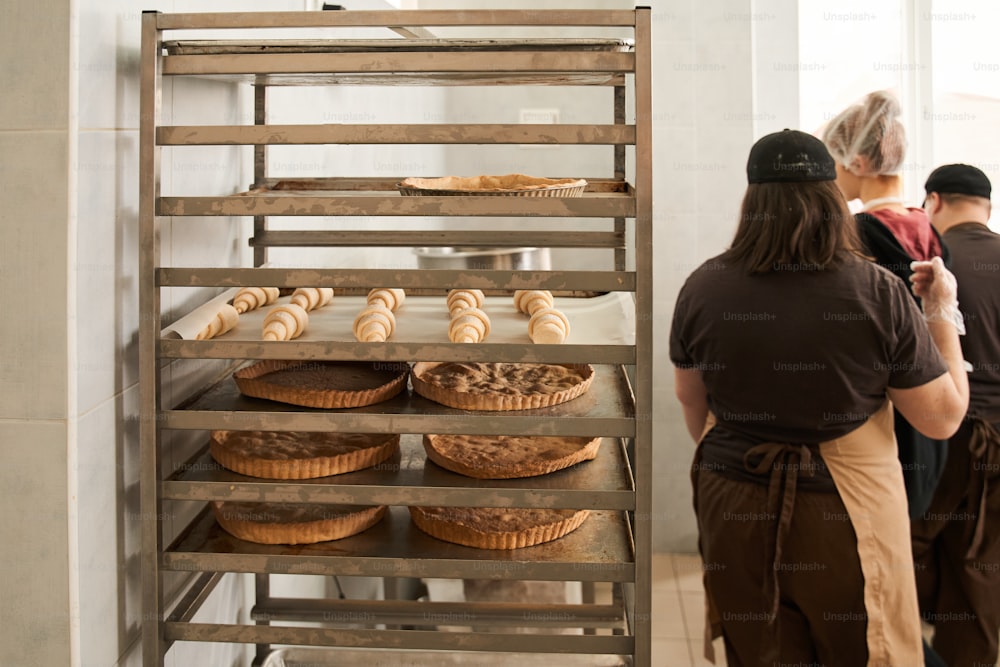 Bräter im Wagen. Blick auf die Kuchenformen, die am Tablett am Wagen der Konditorei stehen. Kuchenproduktionskonzept. Archivfoto