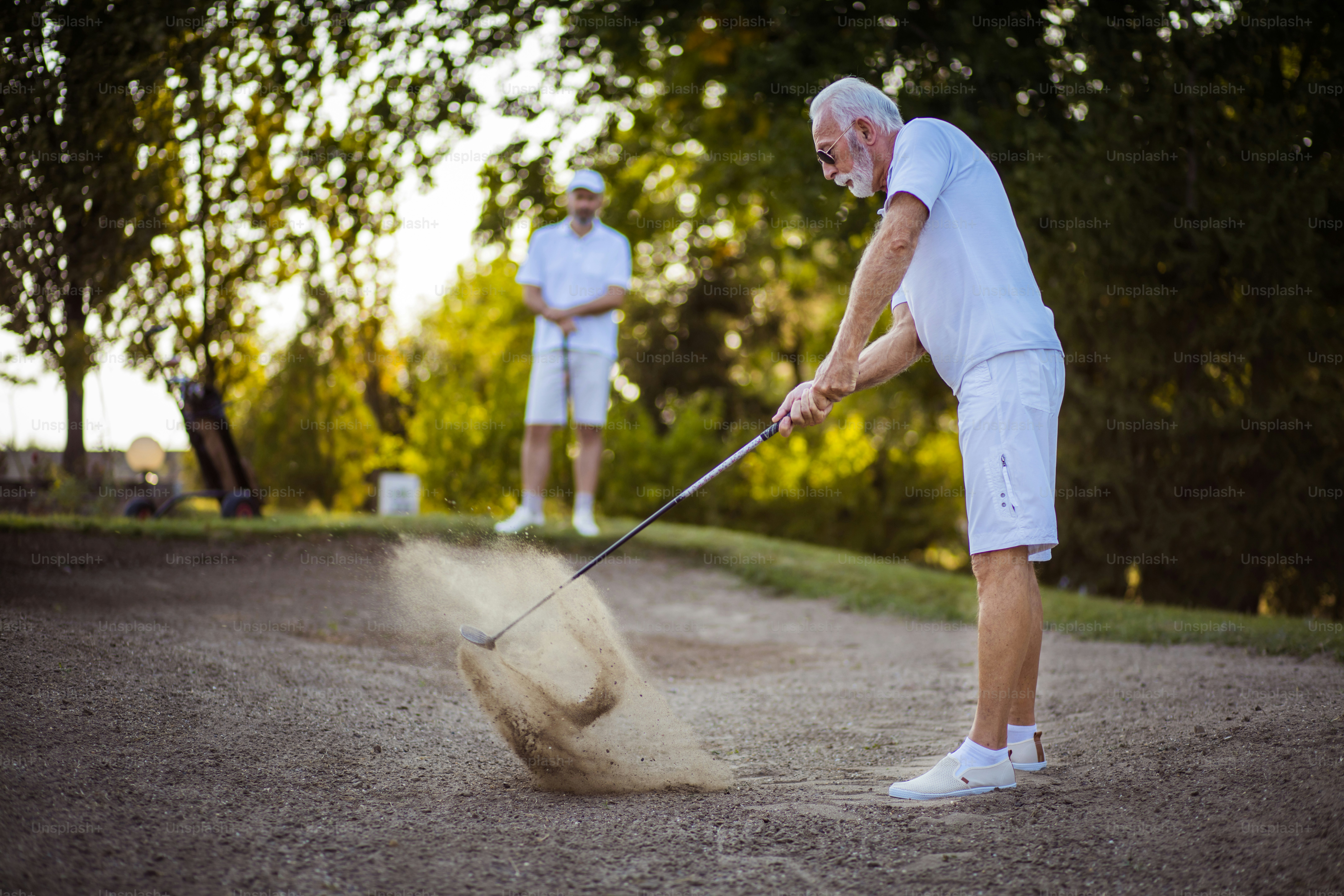 Two men on the golf course. Man hits a golf ball.
