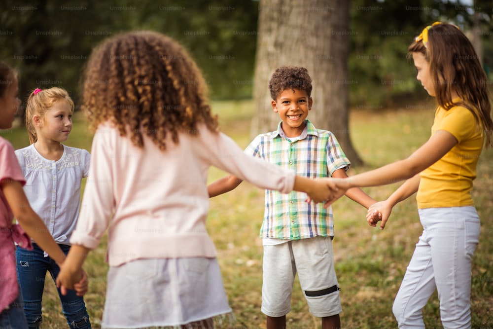 Grande gruppo di bambini della scuola che si divertono nella natura. L'attenzione è sullo sfondo.