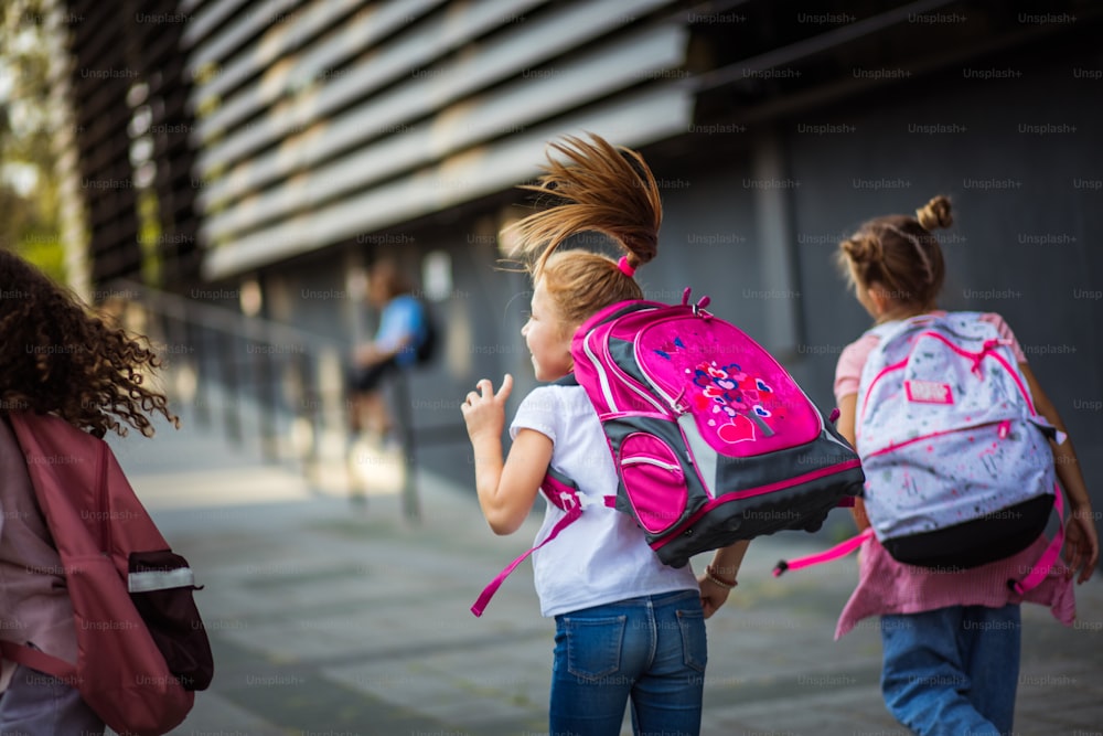 L'anno scolastico è iniziato. Tre ragazze che corrono a scuola.