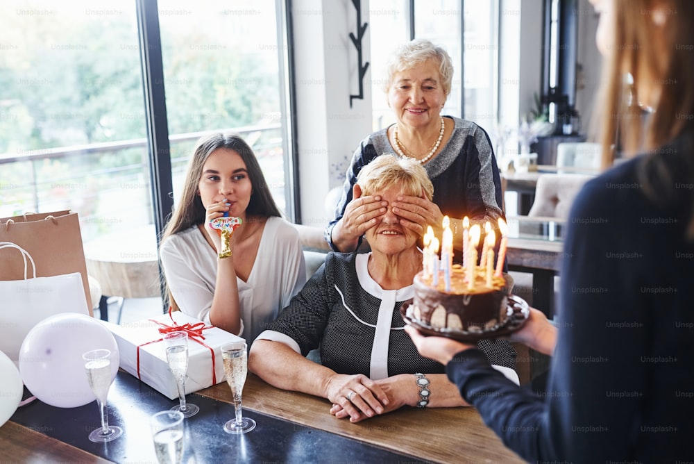 Senior woman with family and friends celebrating a birthday indoors.