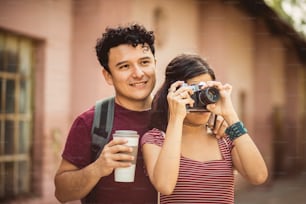 Young couple standing on street. Girl uses a camera.