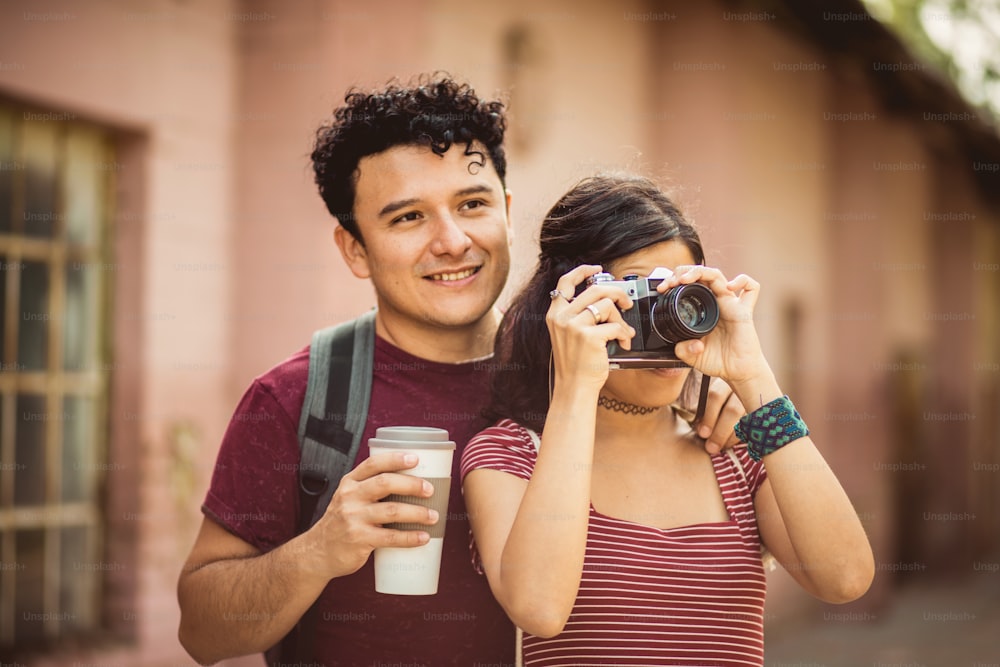 Young couple standing on street. Girl uses a camera.