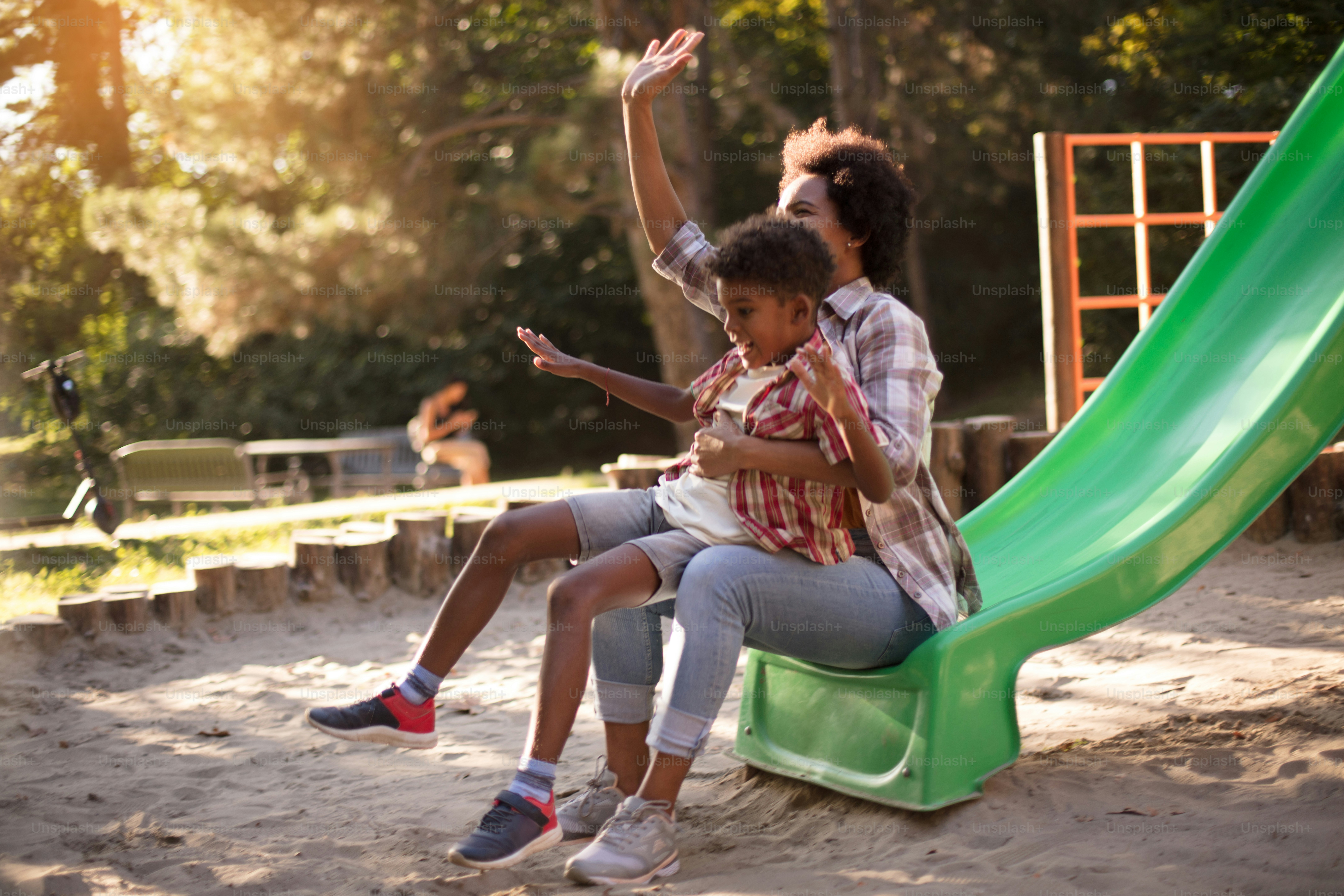 Funny time.  African American mom playing with child on playground.