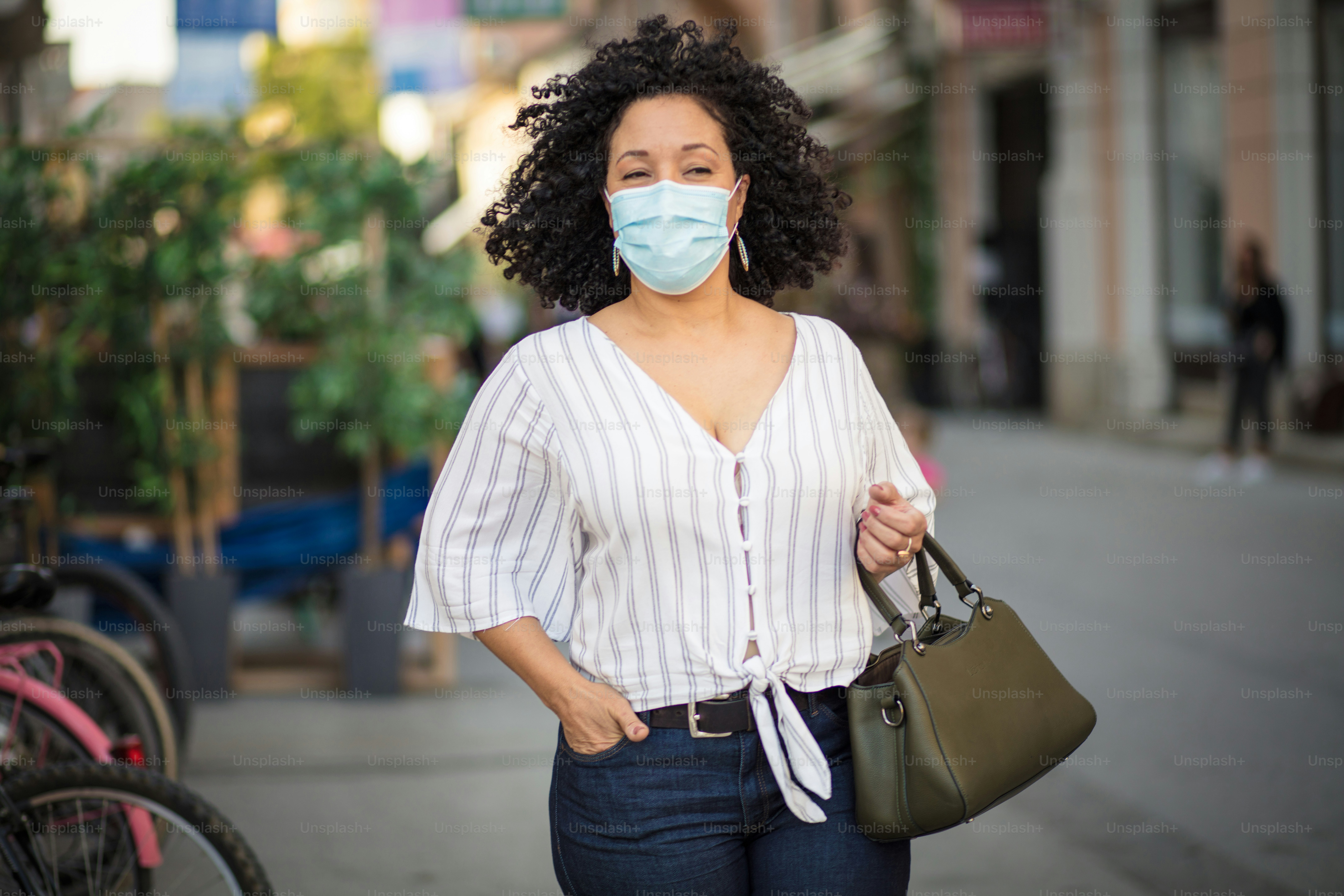 Woman with protective mask on face walking trough city.