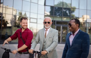 Three business man on street. Two men with electric scooter.