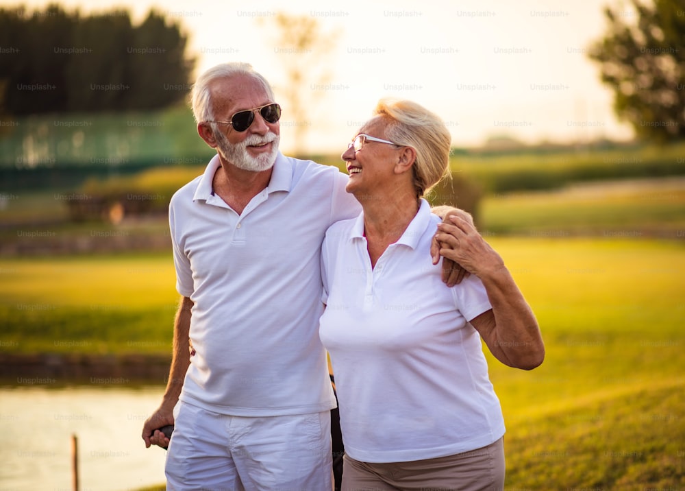 Coppia sorridente di golfisti anziani.