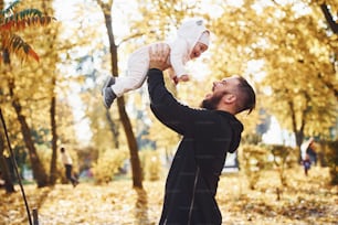Il padre in abiti casual con il suo bambino è nel bellissimo parco autunnale.