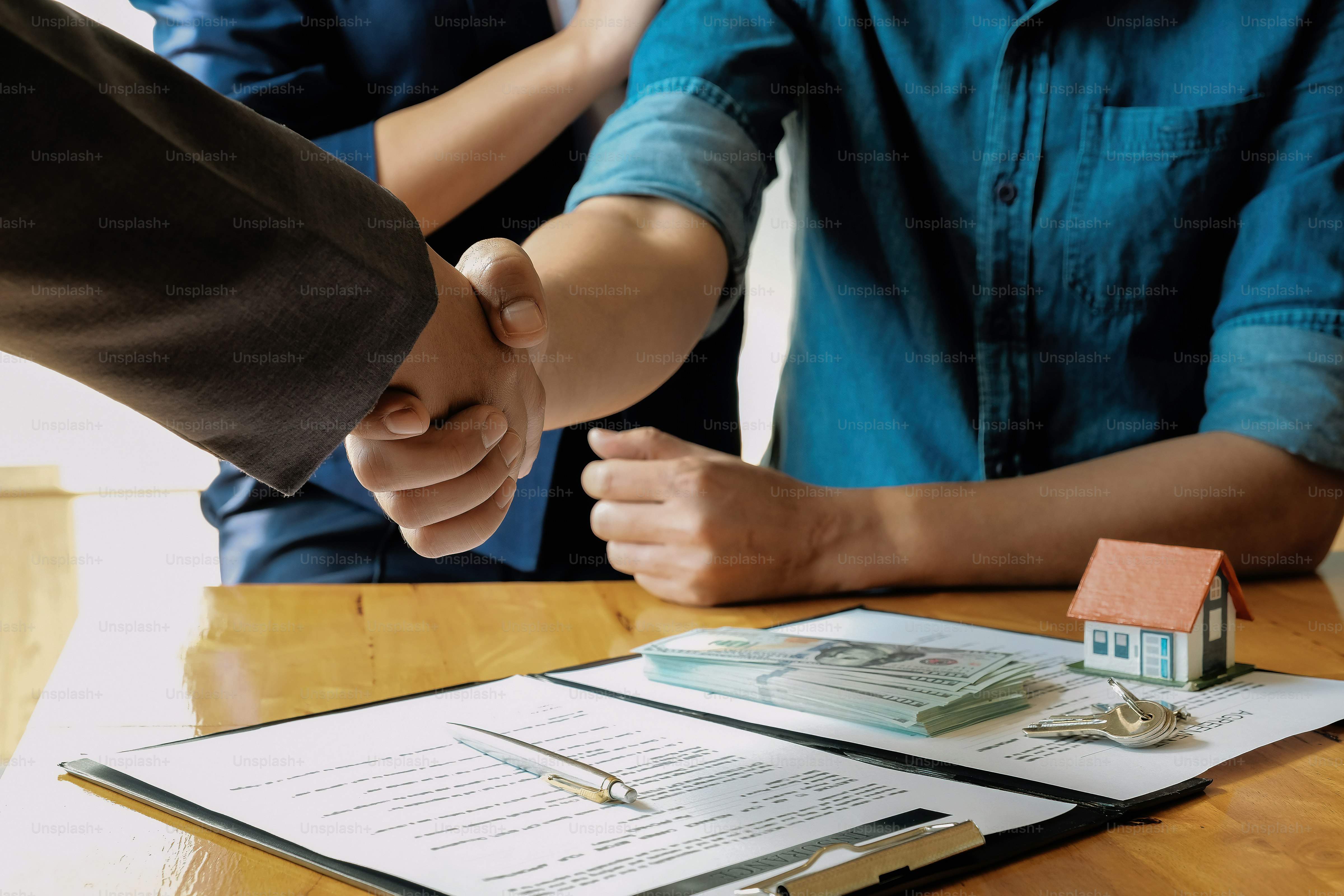 married couple and friendly Real Estate Agent shaking hands after making real estate deal indoors, above view