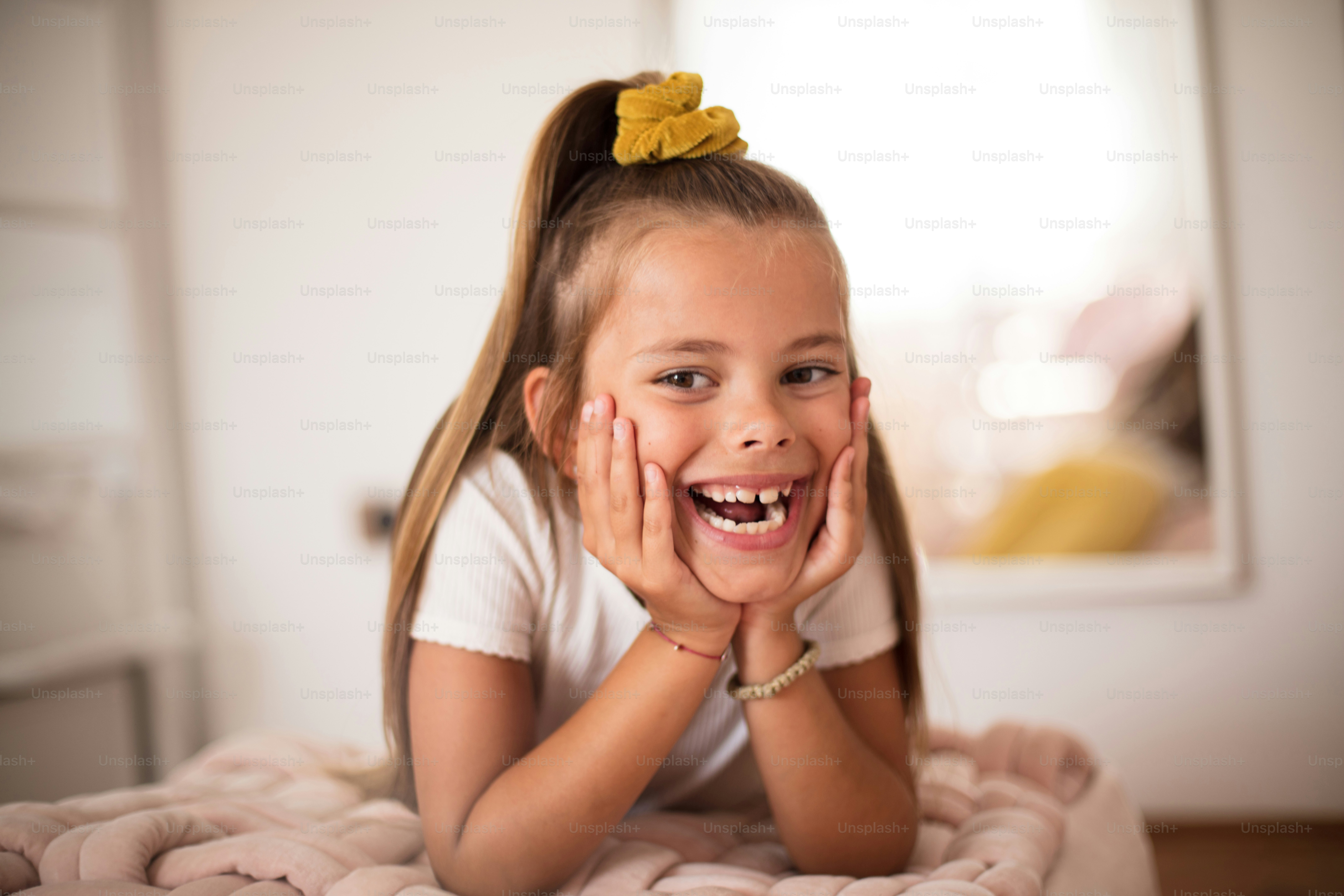 Smiling little girl in bedroom alone. Looking at camera.