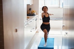 Charming Afro American lady in sportswear doing yoga exercise and smiling