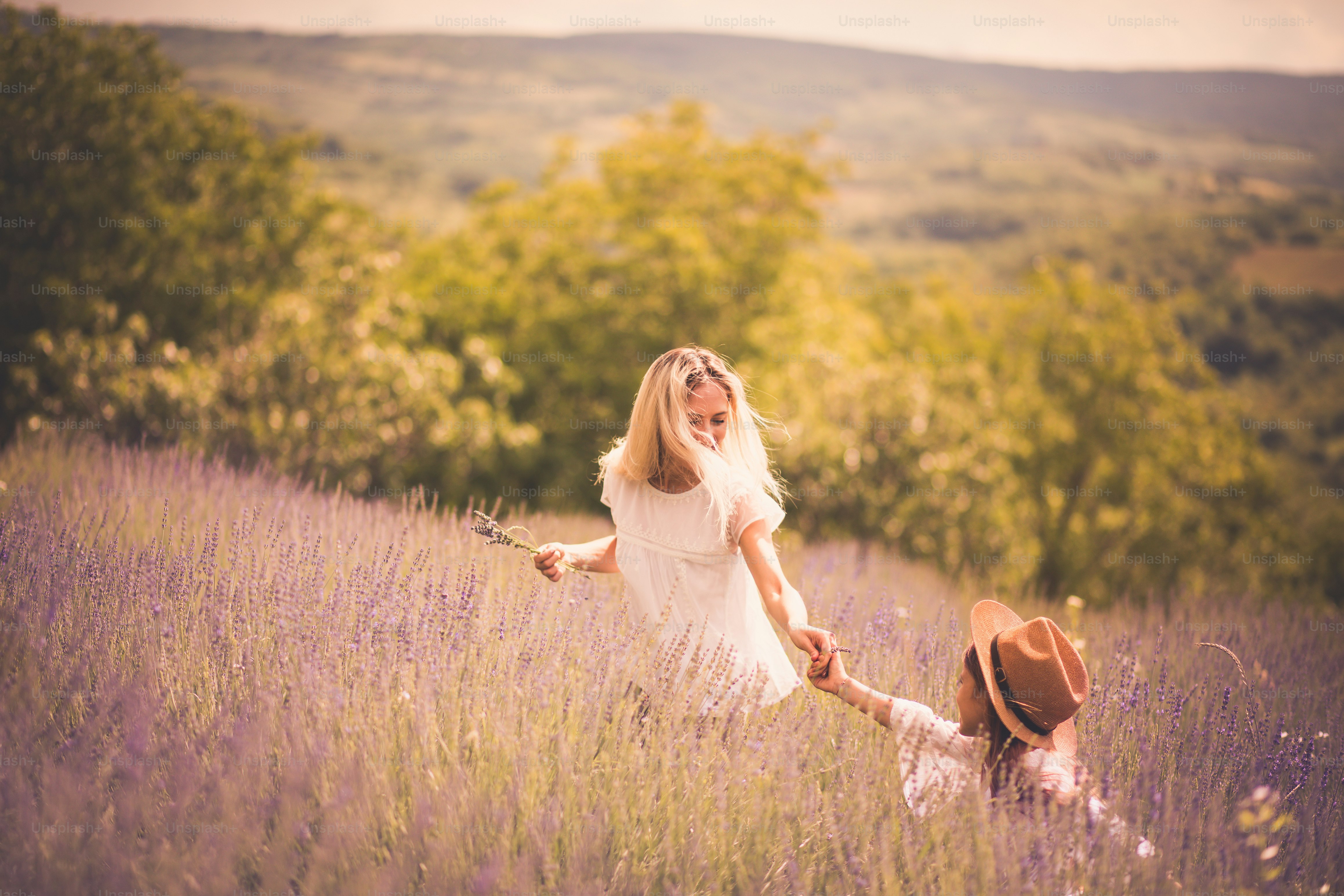 Ibu dan anak perempuan berlari melalui ladang lavender.