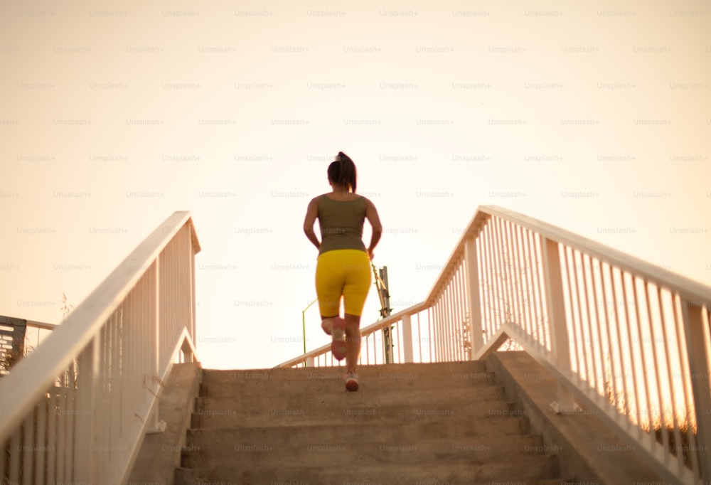 African woman jogging on the stairs. View from back.