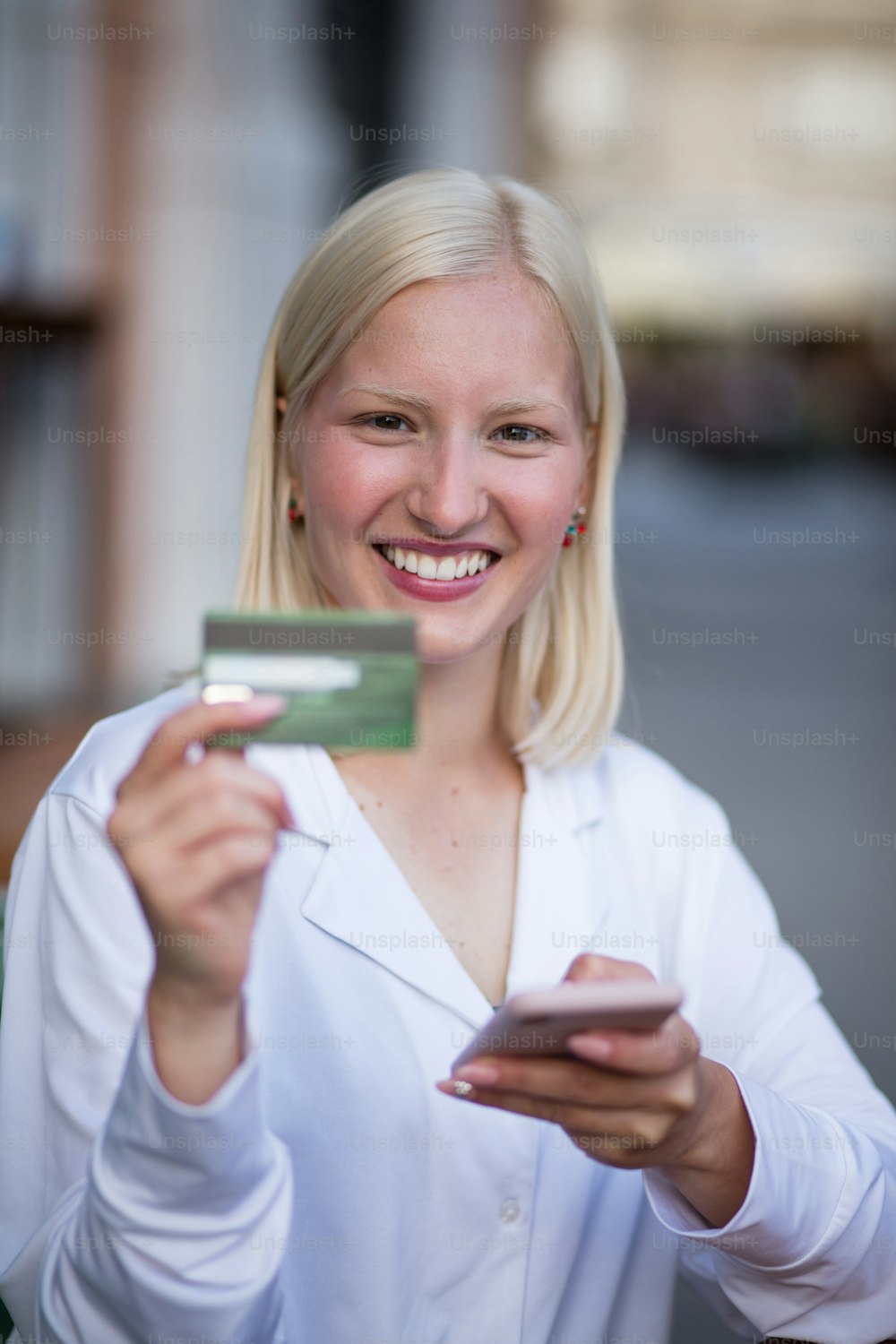 Mujer que usa un teléfono inteligente y una tarjeta de crédito para comprar en línea en una cafetería.