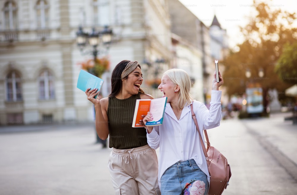 Two woman on the street carrying books.