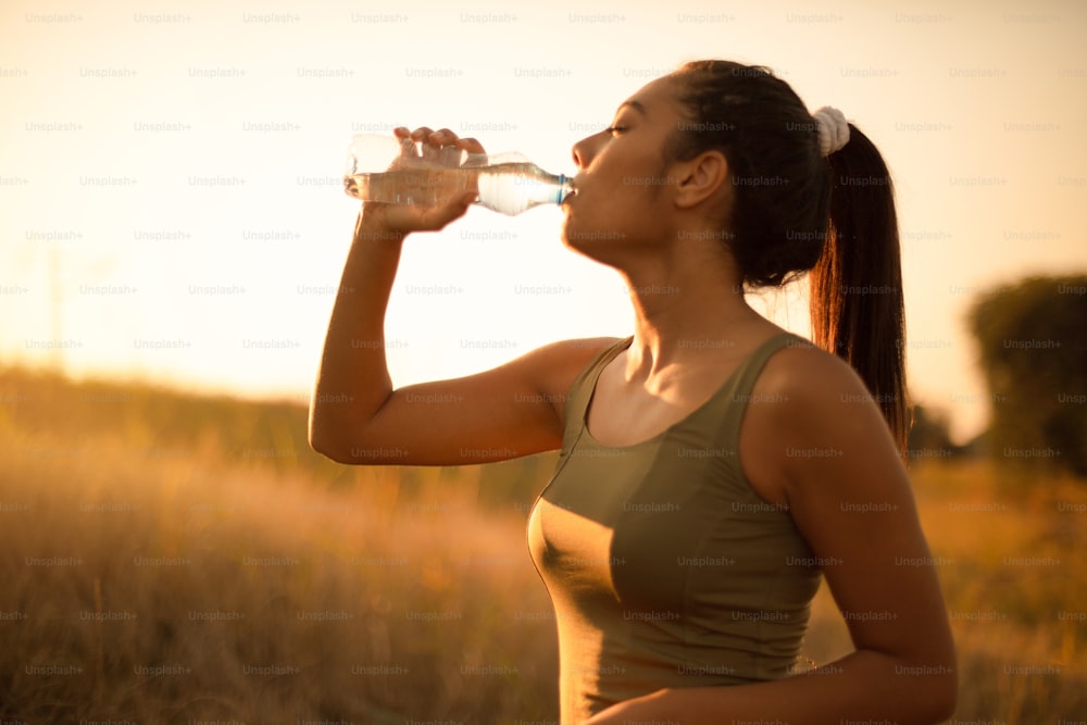 Jeune femme sportive buvant de l’eau à l’extérieur.