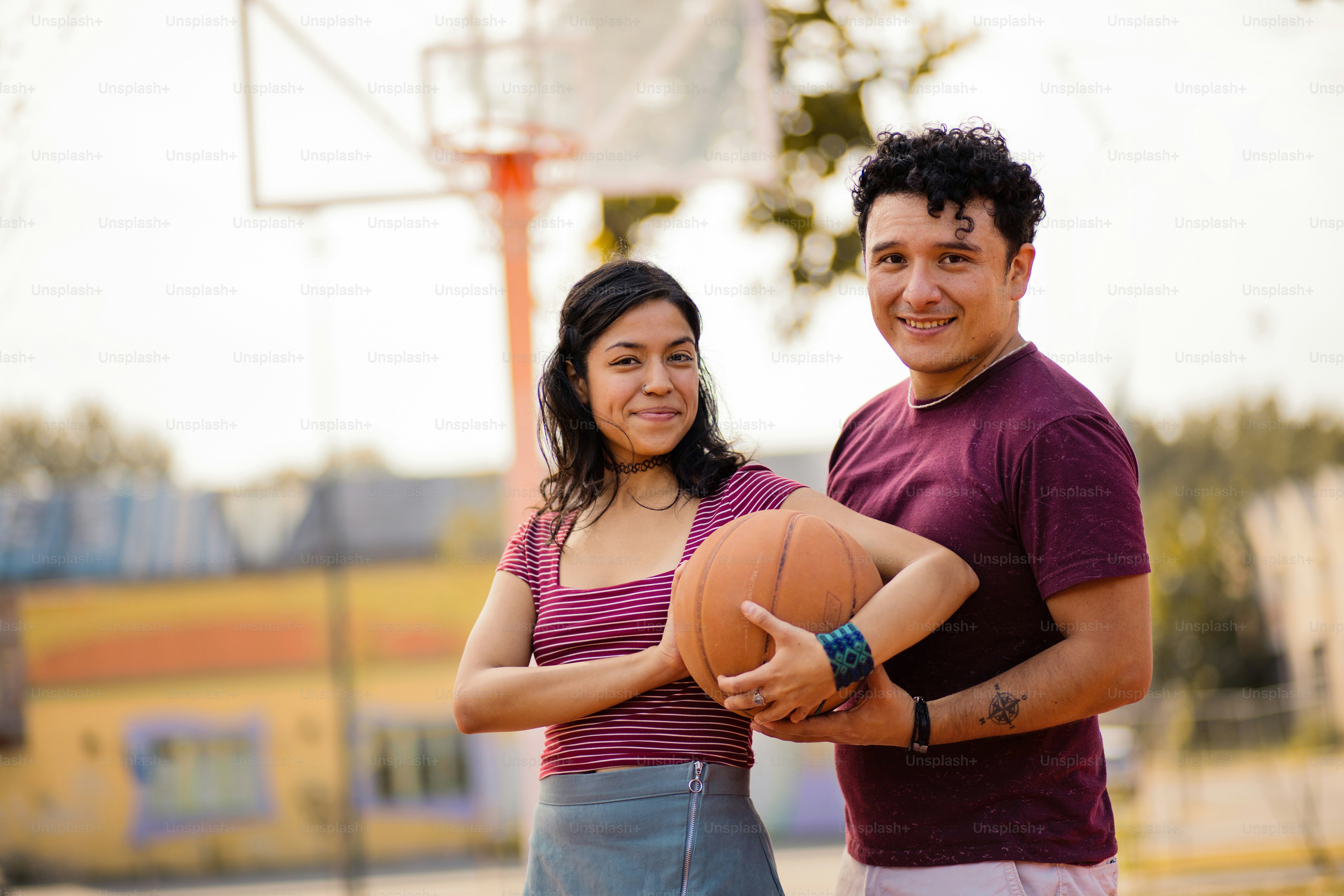 Jeune couple avec ballon sur le terrain de basket-ball.