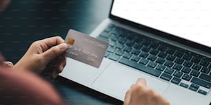 Mains tenant une carte de crédit en plastique et utilisant un ordinateur portable. Concept d’achat en ligne. Image tonique