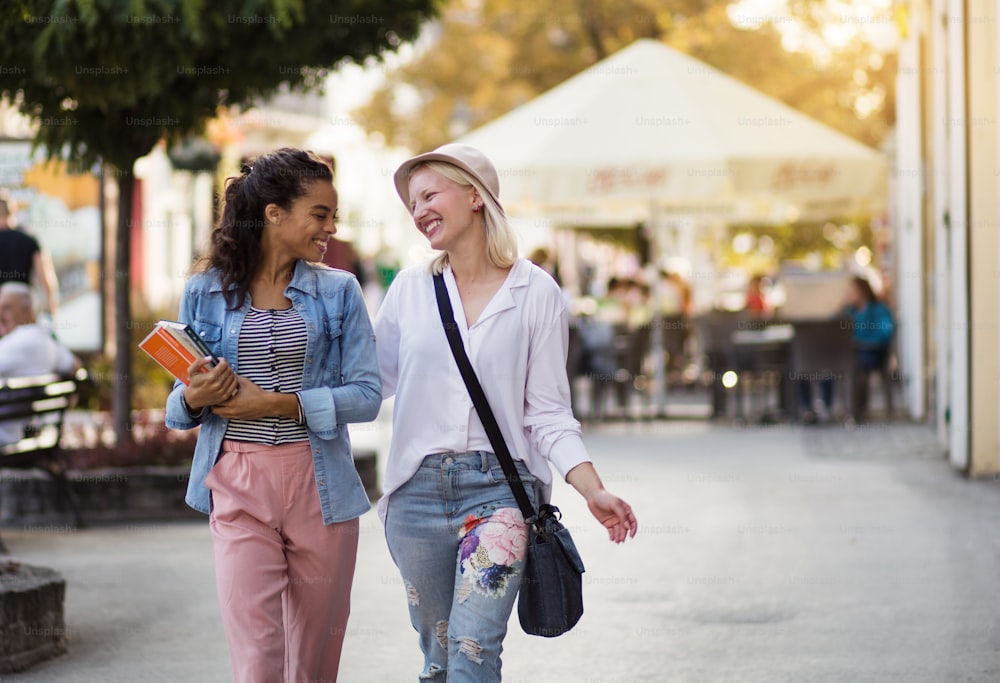 Two woman on the street carrying books.