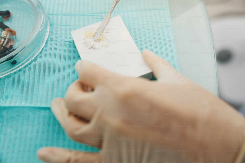 Ortodontista che mescola la polvere di cemento dentale con l'olio durante la creazione dell'otturazione dentale su mattoni di plastica espansa
