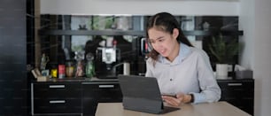Smiling businesswoman holding mobile phone and searching information on computer tablet in office.
