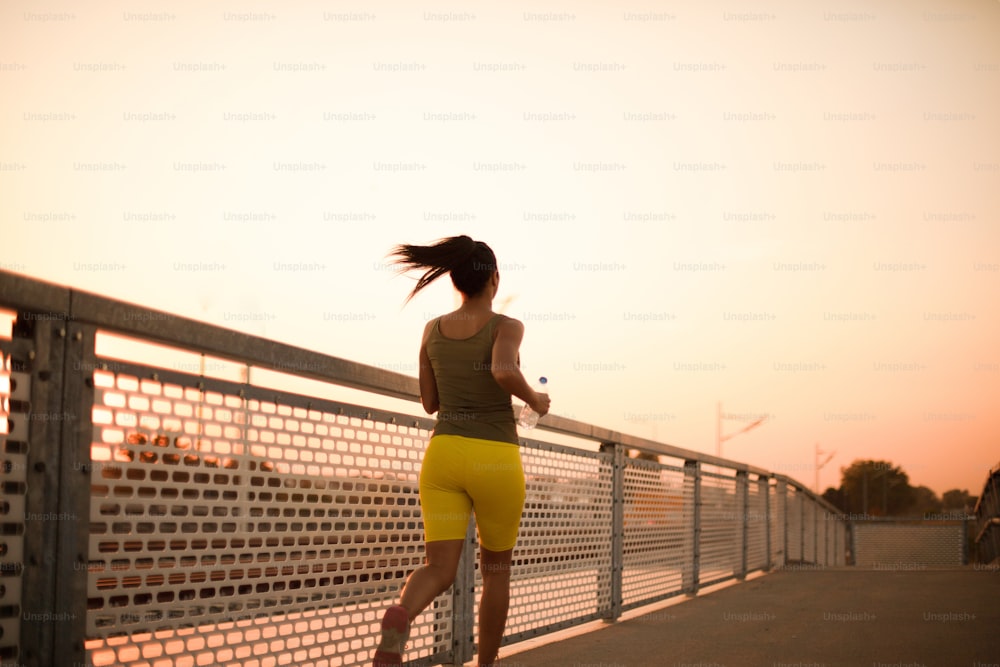 Donna africana che fa jogging sul ponte. Vista da dietro.