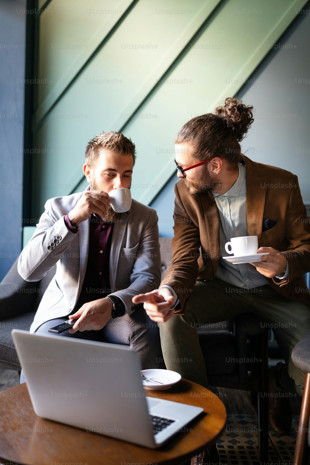 Happy young attractive business man friends talking in cafe