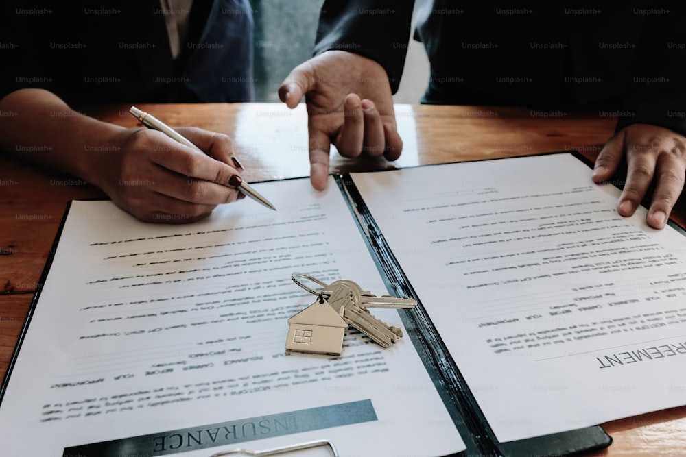 不動産業者は、家を買うか売るための顧客の署名契約の署名のための手を提供します。不動産のコンセプト コンタクト契約のコンセプト - 選択的焦点