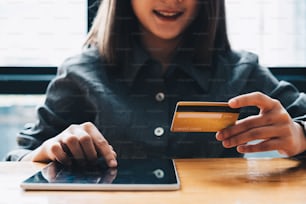 Young woman holding credit card and using tablet computer. Online shopping concept.