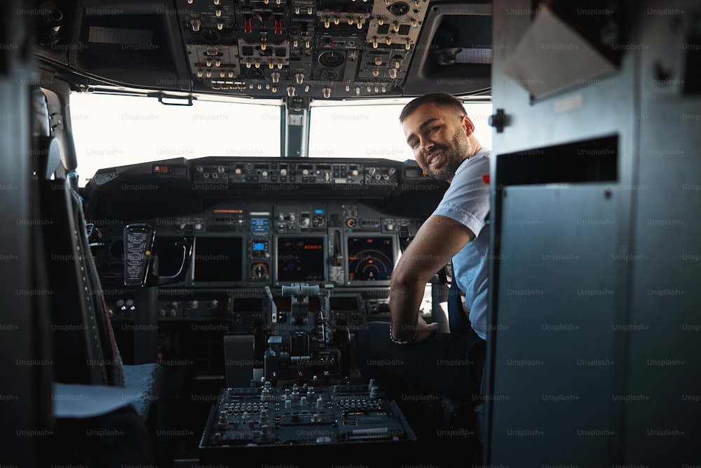 View of the cockpit with a young handsome pilot sitting in it and turning back with a friendly smile